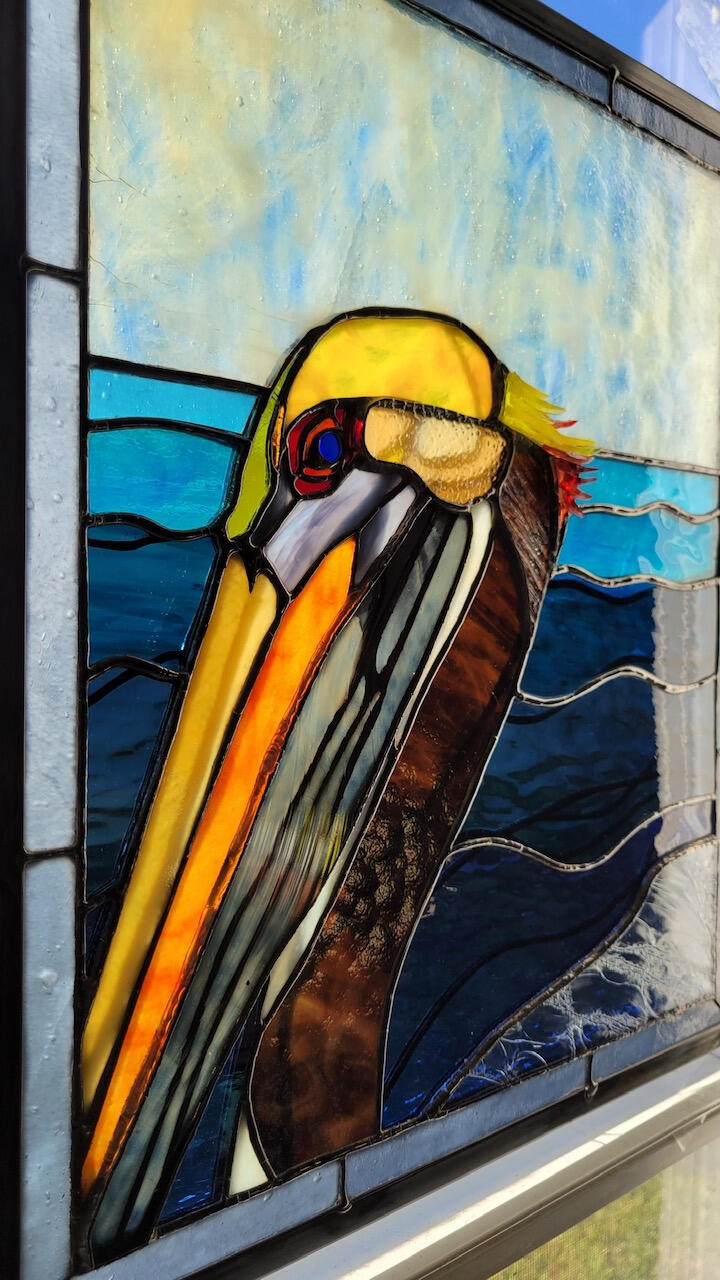 oblique view to show 3D details of additional spot plating on the water and folded pouch, and to show the slivers of glass added to the back of the pelican’s head